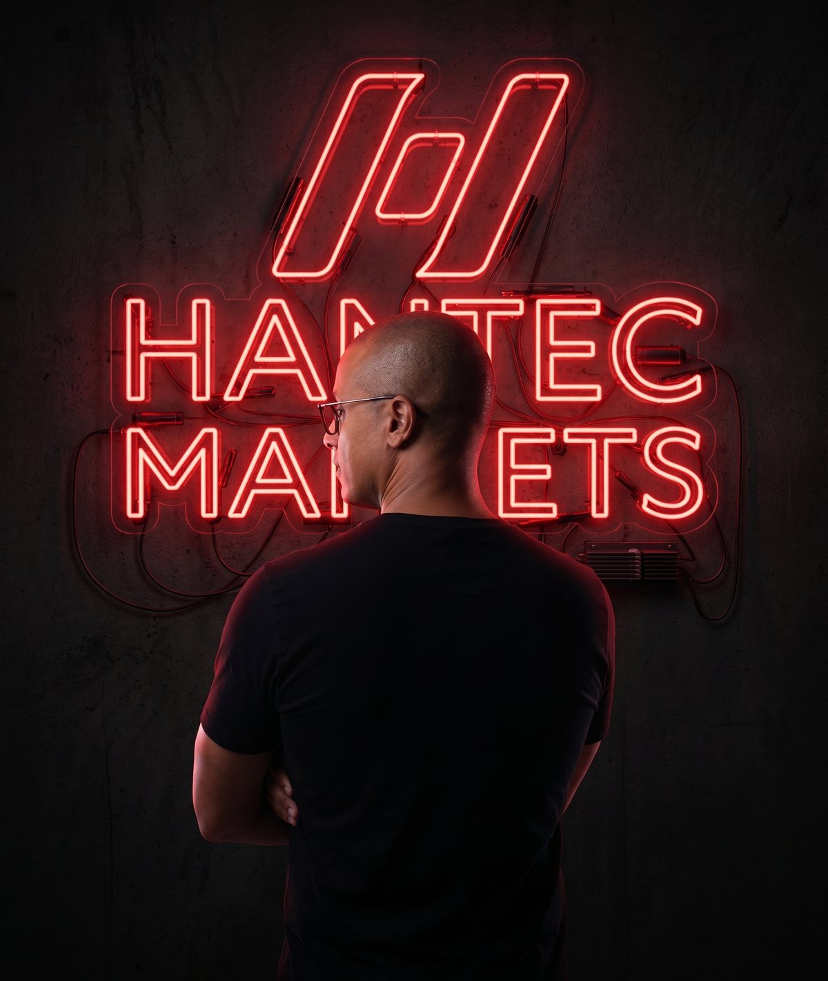 Filipe Bruno diante do letreiro de neon da Hantec Markets